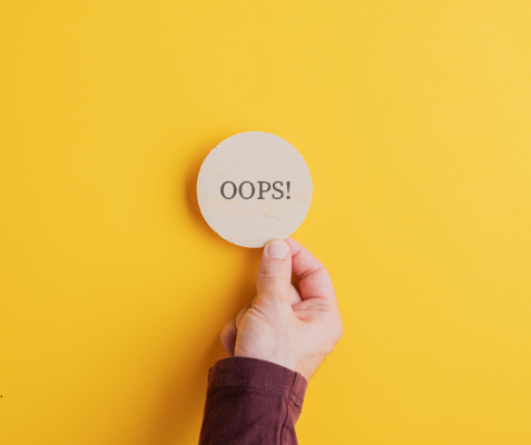yellow background, oops sign on circular wooden disk